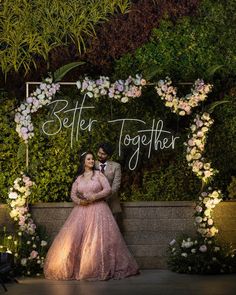 a bride and groom pose for their wedding photo in front of an archway with flowers