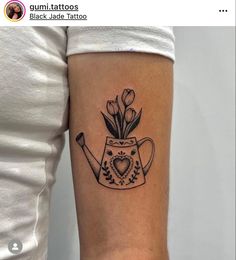 a black and white tattoo of a watering can with tulips on the arm