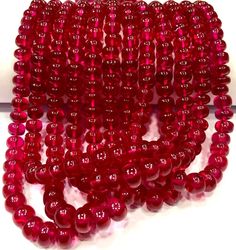 red glass beads are lined up on a white surface