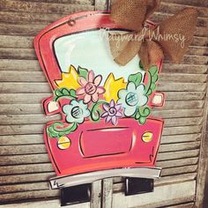 an old red car painted with flowers and burlock on the side of it