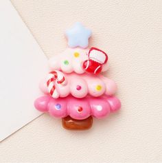 a pink brooch with a candy tree on it's side and a white card in the background