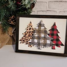 three christmas trees are displayed in a wooden frame