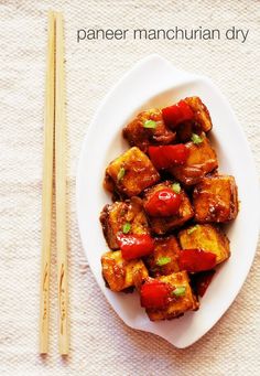 a white plate topped with tofu next to chopsticks