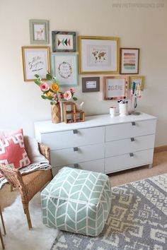 a living room with pictures on the wall and an ottoman in front of it,