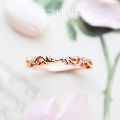 a close up of a gold ring on a white surface with flowers in the background