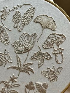 a close up of a embroidery pattern on a white piece of cloth with flowers and leaves