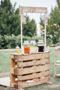 an outdoor bar made out of wooden pallets with drinks on the table and jars