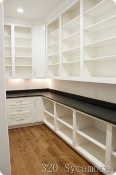 an empty kitchen with white cabinets and black counter tops, wood flooring and hard wood floors