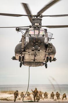 an army helicopter is hooked up to the ground with soldiers in uniform around it and onlookers nearby