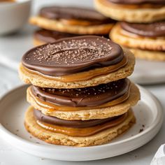 a stack of cookies with chocolate frosting and sprinkles on white plates