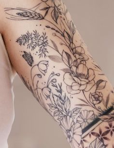 a woman's arm with flowers and leaves on it