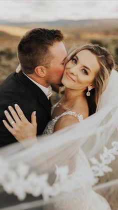 a bride and groom kissing in the desert