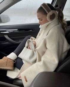 a woman sitting in the back seat of a car with her purse and headphones on