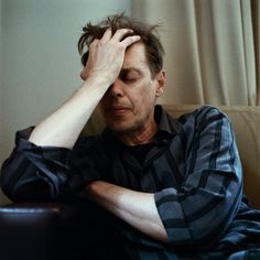 a man sitting on top of a couch holding his head