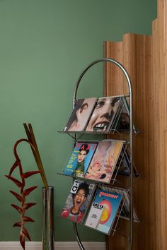 a magazine rack with magazines on it next to a potted plant