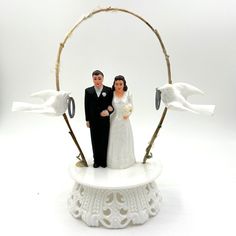 a wedding cake topper with a bride and groom in front of an arch made out of birds