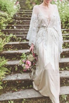 a woman in a white dress is walking down some steps with flowers on her head