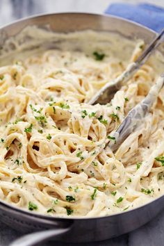 a pan filled with pasta and parsley on top of a table