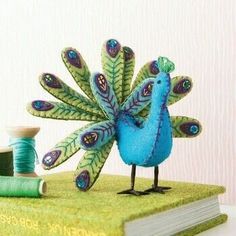 there is a small blue bird on top of a book with spools of thread