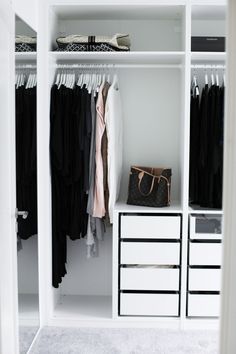 an organized closet with white drawers, black and white clothes hanging on the rails and handbags