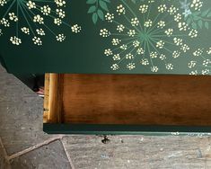 a green bench with white flowers painted on it