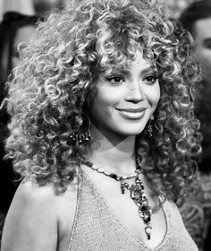 a black and white photo of a woman with long curly hair, wearing a necklace