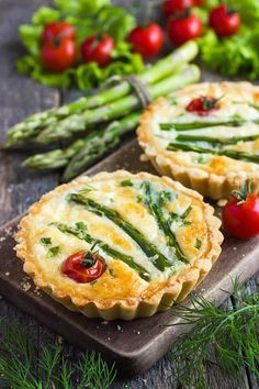 asparagus and cheese mini tarts on a cutting board with vegetables in the background