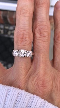 a woman's hand with a three stone ring on top of her left hand