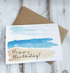 a card with the words happy birthday written in black ink on it, sitting on top of a wooden table