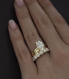 a woman's hand with two gold rings on it and an engagement ring in the middle