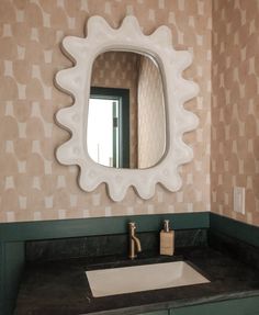 a bathroom sink with a mirror above it and a soap dispenser on the counter