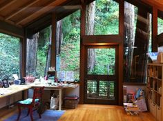 the inside of a home office with lots of windows and wood flooring in front of it