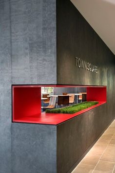 the inside of a building with red shelves and grass growing on it's side