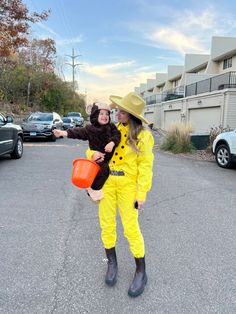 two people dressed in yellow and black posing for the camera with one holding an orange bucket