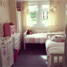 a bedroom with two twin beds, dressers and a teddy bear on the bed