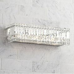 a crystal wall light mounted on the side of a white brick wall in a bathroom