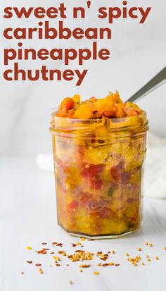 a jar filled with food sitting on top of a white table next to a spoon