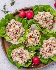 several lettuce cups filled with crab salad on top of green leafy leaves