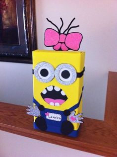 a yellow box with a pink bow on top of it sitting on a wooden shelf