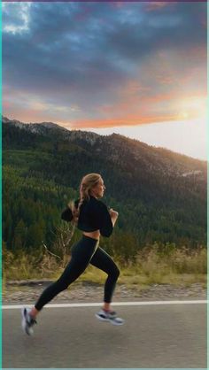 a woman running down the road with mountains in the backgrouds behind her