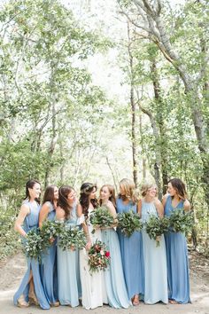 a group of women standing next to each other in front of trees and bushes on a dirt road