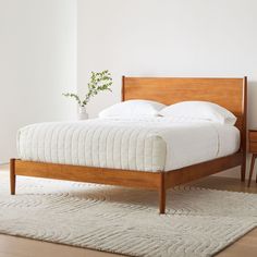 a bed sitting on top of a white rug next to a wooden headboard and foot board