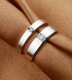 two white gold wedding bands with princess cut diamonds on each side, set in 18k white gold