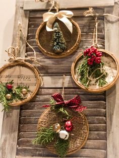 three christmas wreaths hanging from the side of a wooden window sill with pine cones and red berries