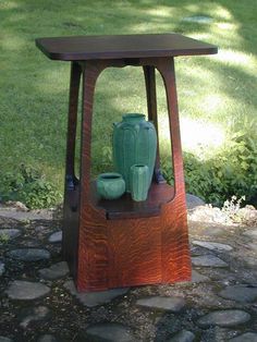 a wooden table with two vases on it in the middle of a park area