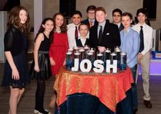 a group of young people standing around a table with bottles on it and the word joshua written in large letters