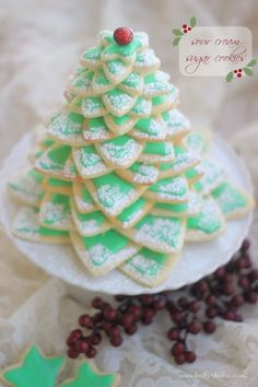 christmas tree cookies on a plate with holly decorations and cranberries around the edges