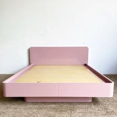 a pink bed sitting on top of a carpeted floor next to a white wall