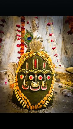 an elaborately decorated green and yellow mask with feathers on it's head, surrounded by other decorative items