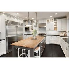 a large kitchen with white cabinets and wooden counter tops, along with stainless steel appliances